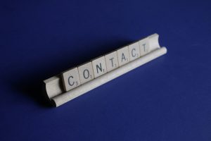 Contact spelled out in letter tiles on a dark blue background